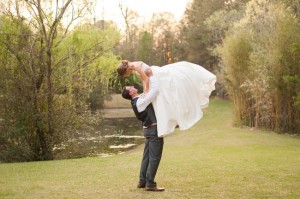 groom-lifting-bride-over-her-head-in-field